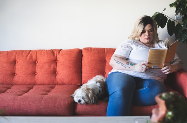 mulher sentada no sofá lendo um livro