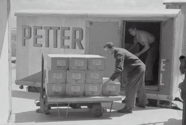 homem carregando caixas no carrinho de carga